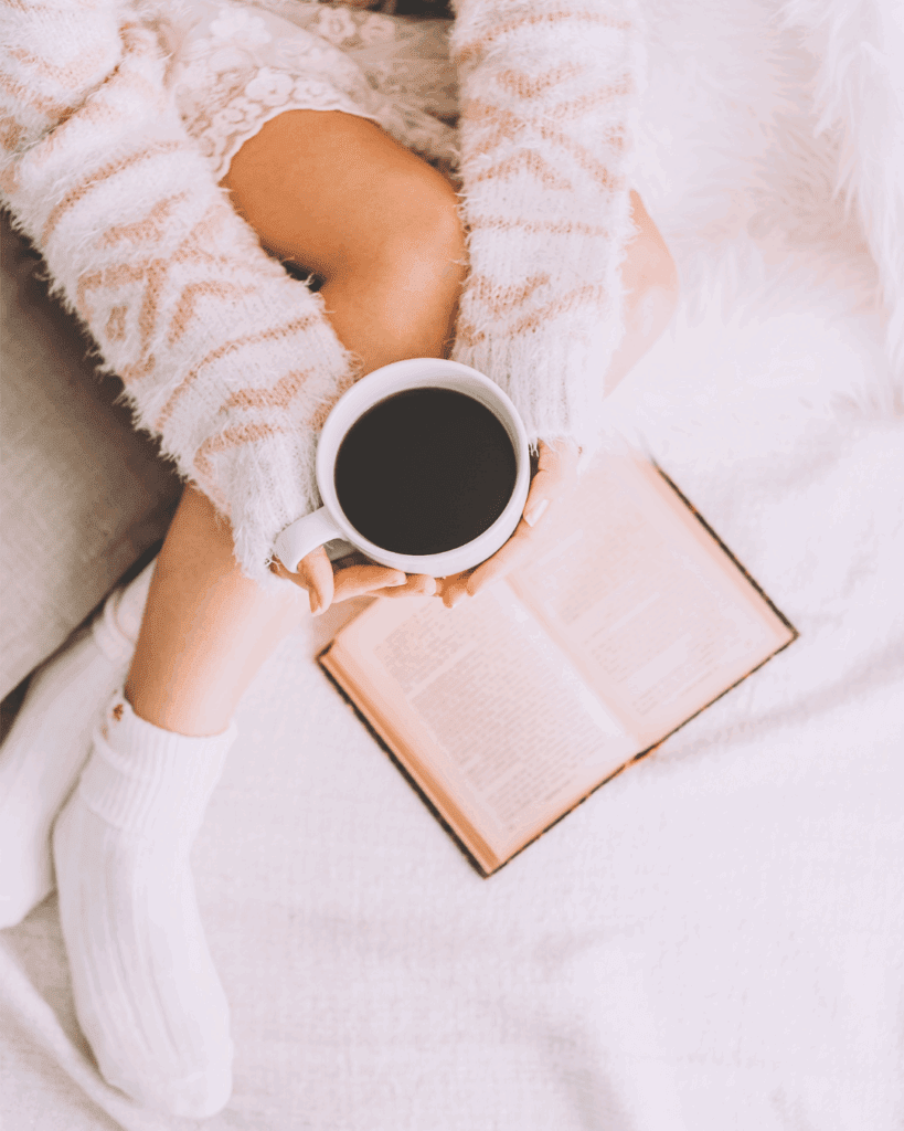 Woman reading a book and sipping tea during her bedtime screen-free routine