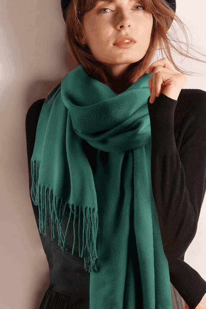 Woman wearing a soft pashmina wrap around her neck with a cozy sweater, perfect for layering on cool flights.