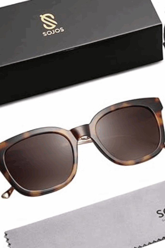 Woman wearing oversized black sunglasses and a white tank top, holding iced coffee – chic summer accessory under $40.
