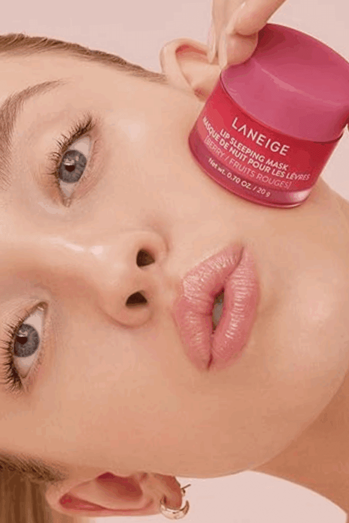 Close-up of LANEIGE Lip Glowy Balm jar sitting on a woman’s cheek – glossy hydrating lip balm for daily use.