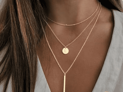 A woman's neck wearing a three layered gold necklace.