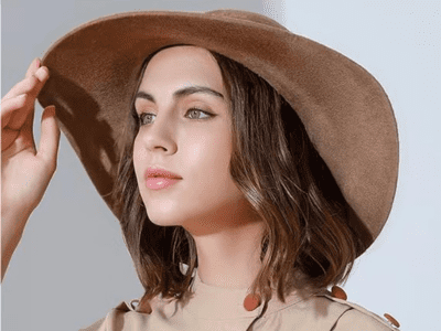 A woman is wearing a brown wide brim felt hat.